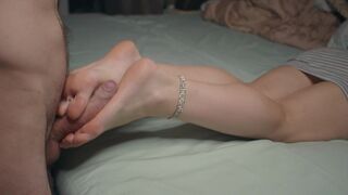 A petite girl shows her small feet and performs a foot job