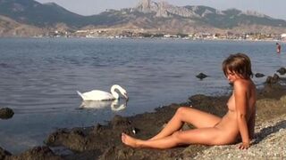 A hot girl is completely naked on the riverbank and masturbates