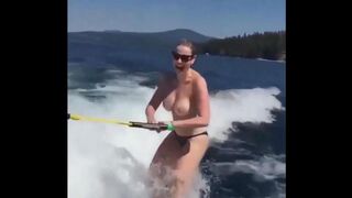 A sexy girl is water-skiing completely naked, her body glistening wet