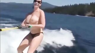 A sexy girl is water-skiing completely naked, her body glistening wet