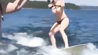 A sexy girl is water-skiing completely naked, her body glistening wet
