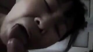 A Chinese woman practices her sucking dick skills on a guy in bed