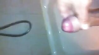 The kid masturbates his dick in the shower with his hand