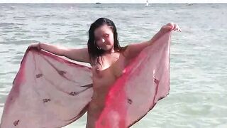 A hot naked girl is having fun on the beach and masturbates