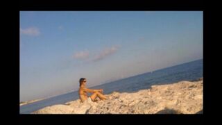A young girl sunbathes naked on the beach