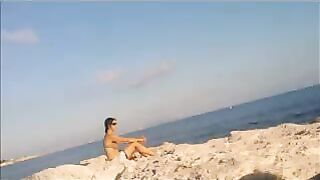 A young girl sunbathes naked on the beach