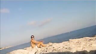 A young girl sunbathes naked on the beach