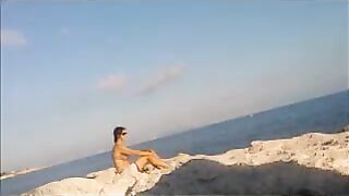 A young girl sunbathes naked on the beach